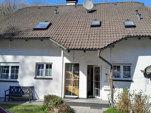 Ferienwohnung Preyersmühle Ein weißes Einfamilienhaus mit Ziegeldach, Satellitenschüssel, Garten und blauem Himmel im Hintergrund.