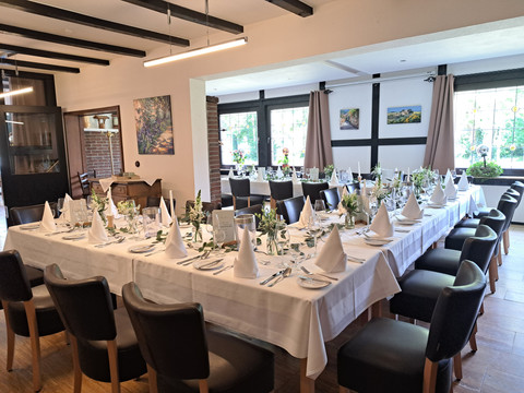 Eimermacher 19.jpg Ein festlich gedeckter langer Tisch in einem eleganten Restaurant mit modernen Holzbalken an der Decke.