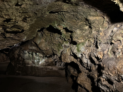 Ansicht Tropfsteinhöhle Eine natürliche Höhle mit erodierten Felswänden, spärlich beleuchtet, zeigt mineralische Ablagerungen.