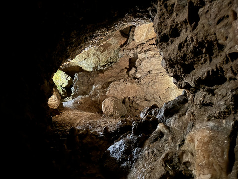 Ansicht Tropfsteinhöhle Natürliche Kalksteinhöhle mit rauen, feuchten Wänden und sanft beleuchtetem, schmalem Durchgang.
