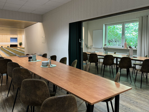 Innenansicht Kegelbahn - Waldhotel Tropfsteinhöhle Eine moderne Kegelbahn mit angrenzendem, einladend eingerichteten Veranstaltungsraum und großen Fenstern.
