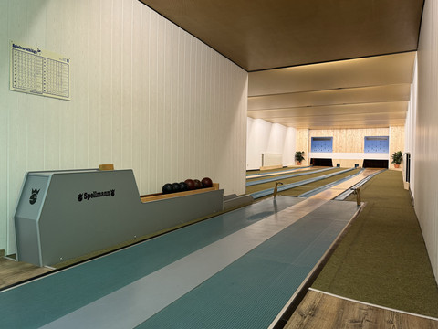 Innenansicht Kegelbahn - Waldhotel Tropfsteinhöhle Kegelbahn mit mehreren Bahnen in einem hell erleuchteten Raum mit Fenstern und Pflanzen im Hintergrund.