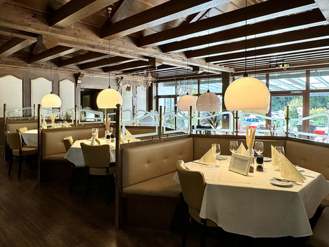 Innenansicht Speisesaal - Waldhotel Tropfsteinhöhle Gemütliches Restaurant mit stilvollen Holzbalken, eleganten runden Tischen und warmem Lichtambiente.