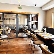 NUENZEHN01_Restaurant_hinten.jpg Innenansicht Gastraum mit Holzfußboden, langer Polstersitzbank rechts, Tischen und Stühlen, modern