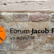 bild_pins_vakalender Forum Jacob Pins Schriftzug mit Logo auf einer rustikalen Bruchsteinmauer.