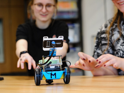 Technische Sammlungen der Stadt Dresden Zwei lachende Frauen testen einen kleinen Roboter auf einem Holztisch.Two smiling women test a small robot on a wooden table.Dvě usměvavé ženy testují malého robota na dřevěném stole.Dwie uśmiechnięte kobiety testują małego robota na drewnianym stole.Twee lachende vrouwen testen een kleine robot op een houten tafel.Due donne sorridenti testano un piccolo robot su un tavolo di legno.
