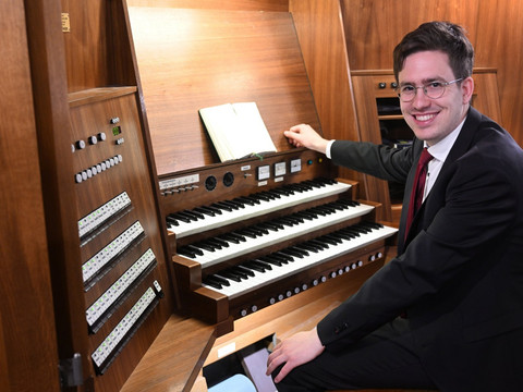 7_14August_cWolfgangSchmidt.JPG Ein Mann in Anzug und Krawatte sitzt lächelnd an einer großen Holzorgel mit mehreren Tastaturen und Knöpfen, ein aufgeschlagenes Buch liegt darauf.A man in a suit and tie sits smiling at a large wooden organ with several keyboards and buttons, an open book lying on top.Muž v obleku a kravatě sedí s úsměvem u velkých dřevěných varhan s několika klávesami a tlačítky, na kterých leží otevřená kniha.Mężczyzna w garniturze i krawacie siedzi uśmiechnięty przy dużych drewnianych organach z kilkoma klawiaturami i przyciskami, a na górze leży otwarta książka.Een man in pak met stropdas zit glimlachend aan een groot houten orgel met verschillende toetsenborden en knoppen, een open boek ligt bovenop.Un uomo in giacca e cravatta siede sorridente a un grande organo di legno con diverse tastiere e pulsanti, con un libro aperto sopra.