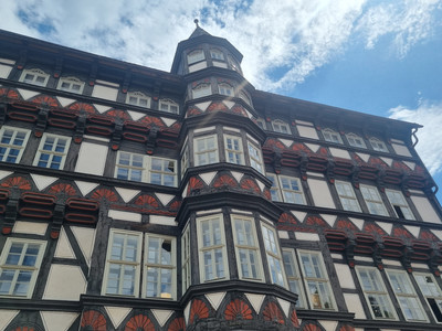 Fachwerkgebäude der alten Münze mit reicher Verzierungen und markantem Erker vor blauem Himmel.