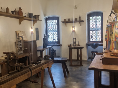 Das Bild zeigt eine historische Druckwerkstatt mit antiken Druckmaschinen und Werkzeugen in der alten Münze.