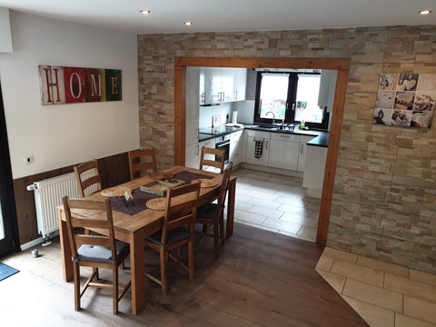 Essbereich Gemütliche Wohnküche mit Esstisch und Stühlen, rustikaler Ziegelsteinwand und moderner Küche.