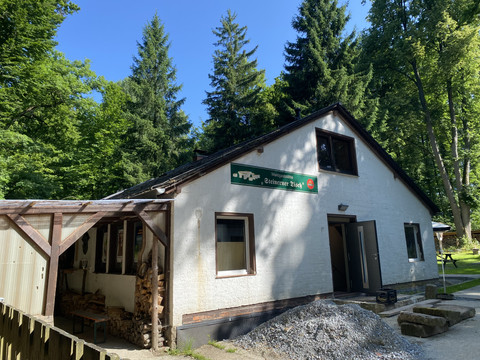 Außenansicht der Waldgaststätte Steinerner Tisch, umgeben von üppigen Bäumen und Natur.