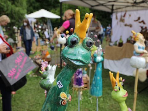 Rosenfest Keramikskulpturen von bunten, fantasievollen Fröschen mit Kronen auf einem Kunsthandwerksmarkt.