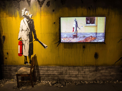 11 House of Banksy - Leipzig - Foto Andreas Schmidt.jpg Kunstwerk im urbanen Stil: Banksy-Gemälde einer Frau mit Gasmaske und Feuerlöscher.Urban-style artwork: Banksy painting of a woman with a gas mask and fire extinguisher.Umělecké dílo v městském stylu: Banksyho malba ženy s plynovou maskou a hasicím přístrojem.Dzieło sztuki w stylu miejskim: obraz Banksy'ego przedstawiający kobietę w masce gazowej i gaśnicy.Urban-style kunstwerk: Banksy-schilderij van een vrouw met gasmasker en brandblusser.Opera d'arte in stile urbano: dipinto di Banksy raffigurante una donna con maschera antigas ed estintore.