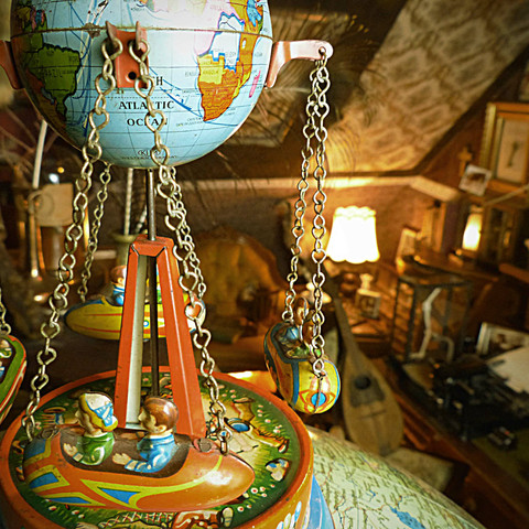 Die Welt in der Stube.jpg Ein nostalgisches Karussell mit einer Weltkugel im Zentrum, umgeben von antikem Interieur.