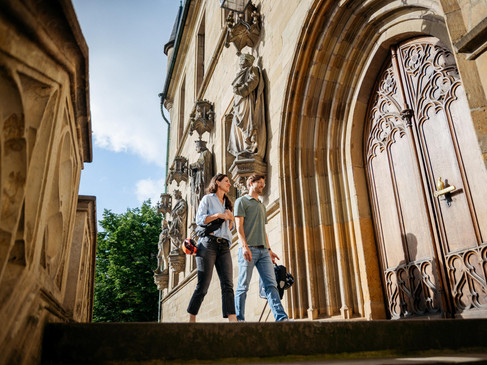 In het historische stadhuis van Osnabrück Twee mensen voor het rijk versierde portaal van het historische stadhuis van Osnabrück, met zijn gotische gevel en stenen figuren.