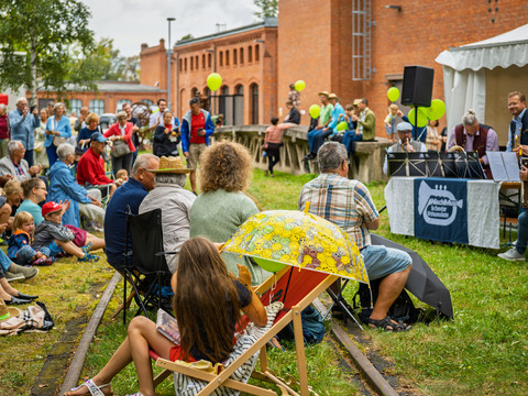 PR_19_Picknickkonzert_2025 (C) Nasser Hashemi.jpg Menschen sitzen auf Stühlen im Freien bei einem Konzert, umgeben von Bäumen und alten Gebäuden.People sitting on chairs outside at a concert, surrounded by trees and old buildings.Lidé sedí na židlích venku na koncertě, obklopeni stromy a starými budovami.Ludzie siedzą na krzesłach na zewnątrz podczas koncertu, otoczeni drzewami i starymi budynkami.Mensen zitten op stoelen buiten bij een concert, omringd door bomen en oude gebouwen.Le persone siedono su sedie all'aperto durante un concerto, circondate da alberi e vecchi edifici.