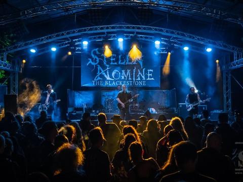 Stella Nomine Festival Torgau4, Fotoquelle_ SchwarzePresse.de, Fotograf Gerald Krauser .jpg Open-Air-Konzert bei Nacht mit Band auf beleuchteter Bühne, Publikum im Vordergrund.