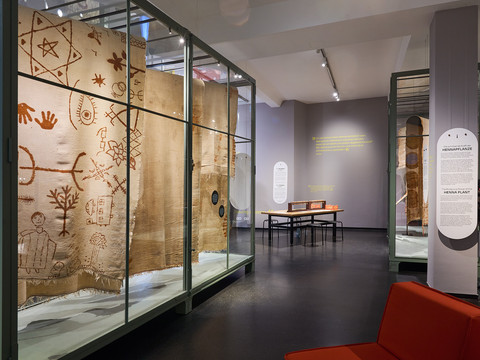 Ausstellung SCHUTZ Foto Tom Dachs.jpg Ausstellung mit antiken Textilien in Glasvitrinen in einem modernen Museumssaal.Exhibition of antique textiles in glass showcases in a modern museum hall.Výstava starožitných textilií ve skleněných vitrínách v moderním muzejním sále.Wystawa zabytkowych tkanin w szklanych gablotach w nowoczesnej sali muzealnej.Tentoonstelling van antiek textiel in glazen vitrines in een moderne museumzaal.Esposizione di tessuti antichi in teche di vetro in una moderna sala museale.