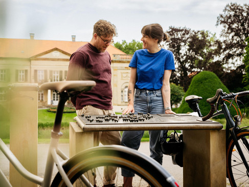 Ein Mann und eine Frau betrachten ein Miniaturmodell eines Parks, umgeben von Fahrrädern.