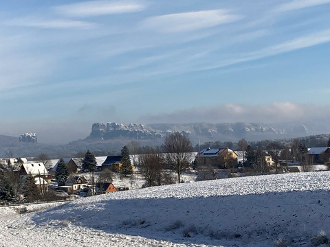Blick zu den Schrammsteinen Winterlicher Ausblick auf das malerische Tafelberg-Panorama der Schrammsteine mit schneebedeckten Feldern.Winter view of the picturesque table mountain panorama of the Schrammsteine with snow-covered fields.Zimní pohled na malebné panorama stolové hory Schrammsteine se zasněženými poli.Zimowy widok na malowniczą panoramę gór stołowych Schrammsteine z pokrytymi śniegiem polami.Winteruitzicht op het schilderachtige tafelbergpanorama van de Schrammsteine met besneeuwde velden.Vista invernale del pittoresco panorama della Schrammsteine con i campi innevati.