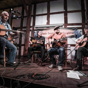 C81B25D6-DB30-42EC-9569-61DF647AC034.jpeg Männer mit Gitarren im Halbkreis sitzend vor einer Fachwerkwand