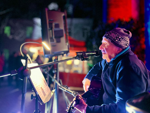 Winterhofnacht Pirna Ein älterer Musiker spielt abends Gitarre, begleitet von stimmungsvollem farbigem Licht.