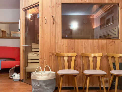 Sauna s dřevěnými stěnami, třemi křesly a velkým oknem v rekreačním domě u Winterbergblicku.