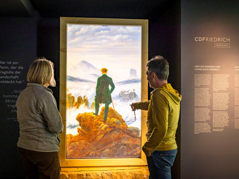 CDFRIEDRICHINSPIRED Zwei Besucher betrachten ein digitales Gemälde von Caspar David Friedrich. Two visitors look at a digital painting by Caspar David Friedrich.Dva návštěvníci si prohlížejí digitální obraz Caspara Davida Friedricha.Twee bezoekers bekijken een digitaal schilderij van Caspar David Friedrich.