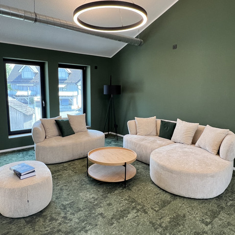 Denkschmiede Moderner Loungebereich der Denkschmiede mit grünen Wänden und hellen Sofas