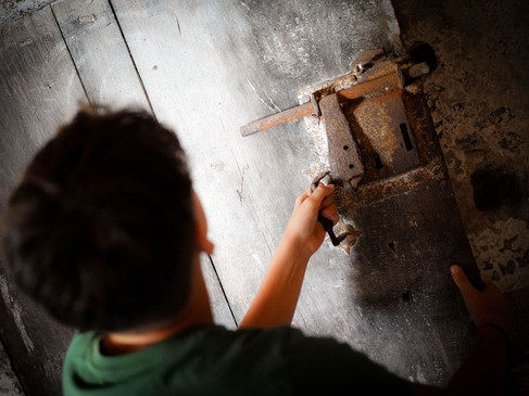 Mensch dreht rustikalen Metallhebel an einer Holztür von oben gesehen.