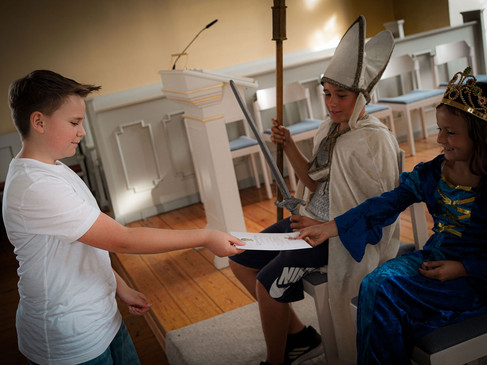 Kinder in Mittelalterkostümen, ein Junge reicht einem sitzenden König ein Dokument.