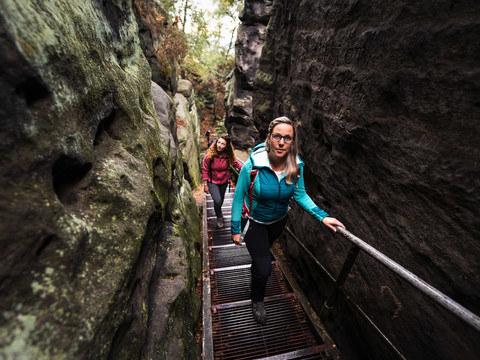 Výstup na Papststein Zwei Frauen steigen eine Metalltreppe in einer engen Felsenschlucht hinauf.
