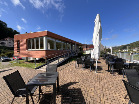 Restaurant mit modernem, rot-getäfeltem Gebäude, großer Fensterfront und ebenerdiger Terrasse