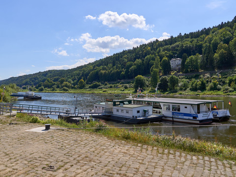 Fähranlegestelle in Bad Schandau, umgeben von bewaldeten Hügeln und dem ruhig fließenden Fluss.