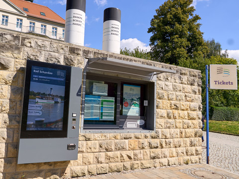 Das Foto zeigt den Ticketverkauf an der Dampfschiff-Anlegestelle in Bad Schandau vor einer Steinmauer.