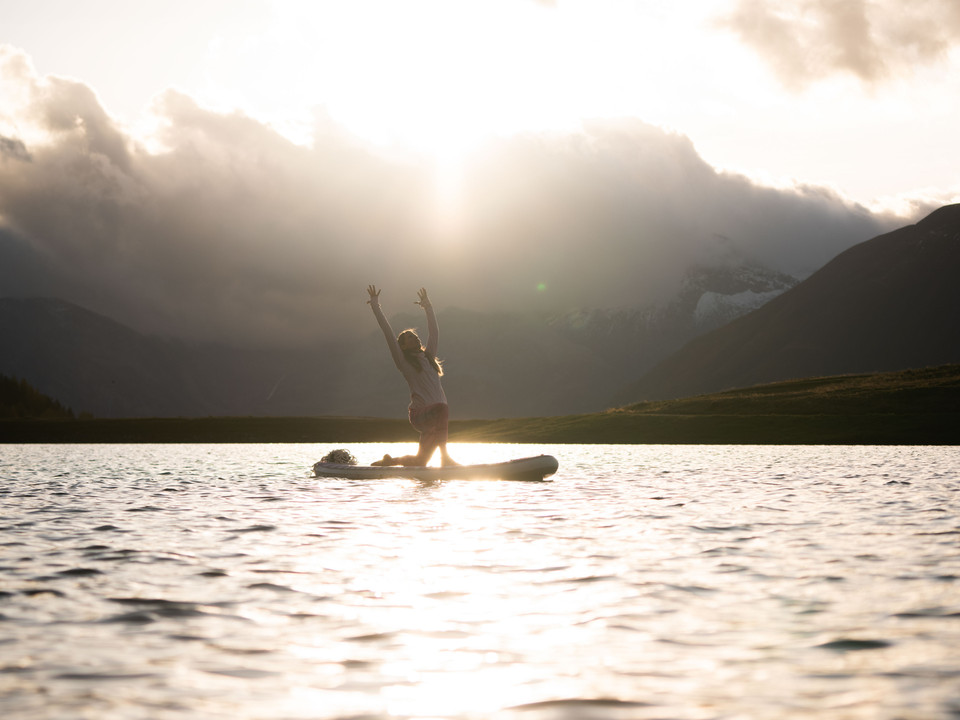 Sonnenuntergangs-Yoga auf dem See Frau macht SUP Yoga Bettmersee im Sommer bei Sonnenuntergang mit goldener Spiegelung auf der Wasseroberfläche und Bergen im HintergrundWoman doing SUP Yoga Bettmersee in summer at sunset with golden reflection on the water surface and mountains in the backgroundFemme faisant du SUP Yoga Bettmersee en été au coucher du soleil avec un reflet doré à la surface de l'eau et des montagnes en arrière-plan