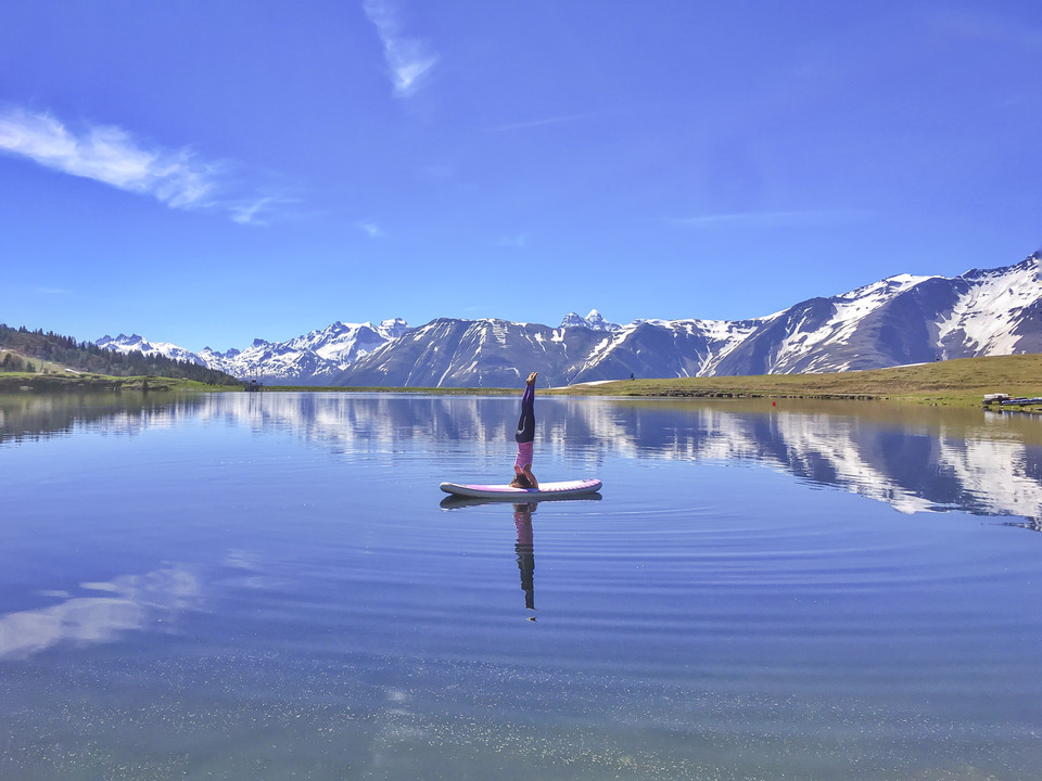 Headstand on SUP Bettmersee Frau macht Kopfstand beim SUP Yoga Bettmersee im Sommer mit atemberaubender Spiegelung der Walliser Alpen im klaren WasserWoman doing a headstand at SUP Yoga Bettmersee in summer with a breathtaking reflection of the Valais Alps in the clear waterUne femme fait le poirier lors d'une séance de SUP Yoga au lac de Bettmersee en été, avec un reflet époustouflant des Alpes valaisannes dans l'eau claire.