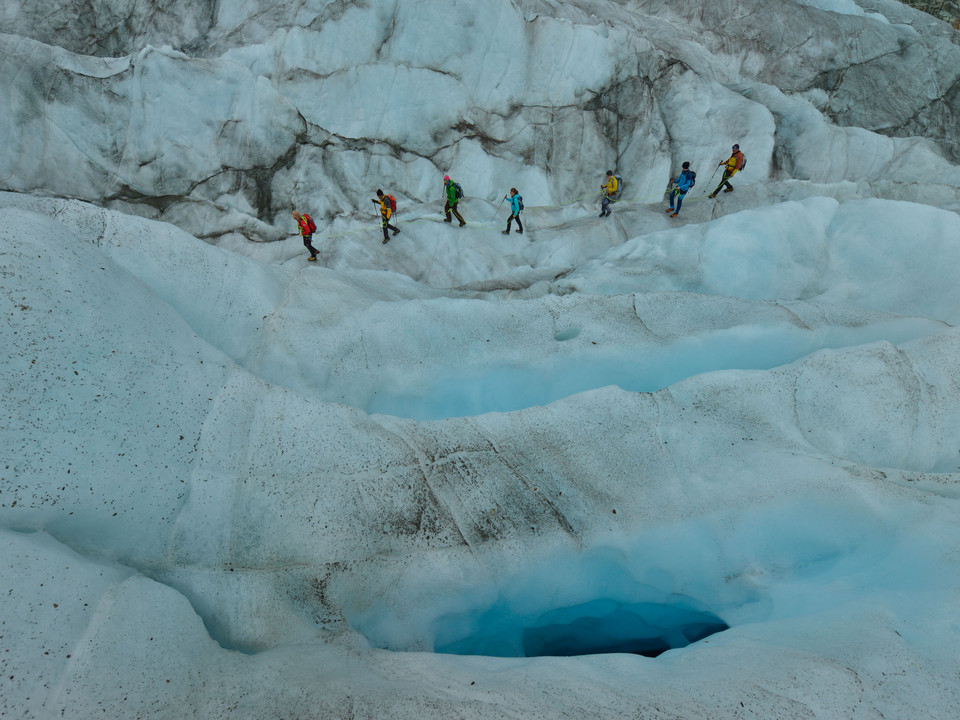 Rope team on the ice of the Aletsch Glacier Teilnehmer der 2-Tage-Gletschertour Aletschgletscher bewegen sich in Seilschaft über blau schimmernde Eisspalten im SommerParticipants on the 2-day Aletsch Glacier tour move in a rope team over shimmering blue crevasses in summerLes participants à la randonnée de 2 jours sur le glacier d'Aletsch se déplacent en cordée sur des crevasses de glace aux reflets bleus en été.