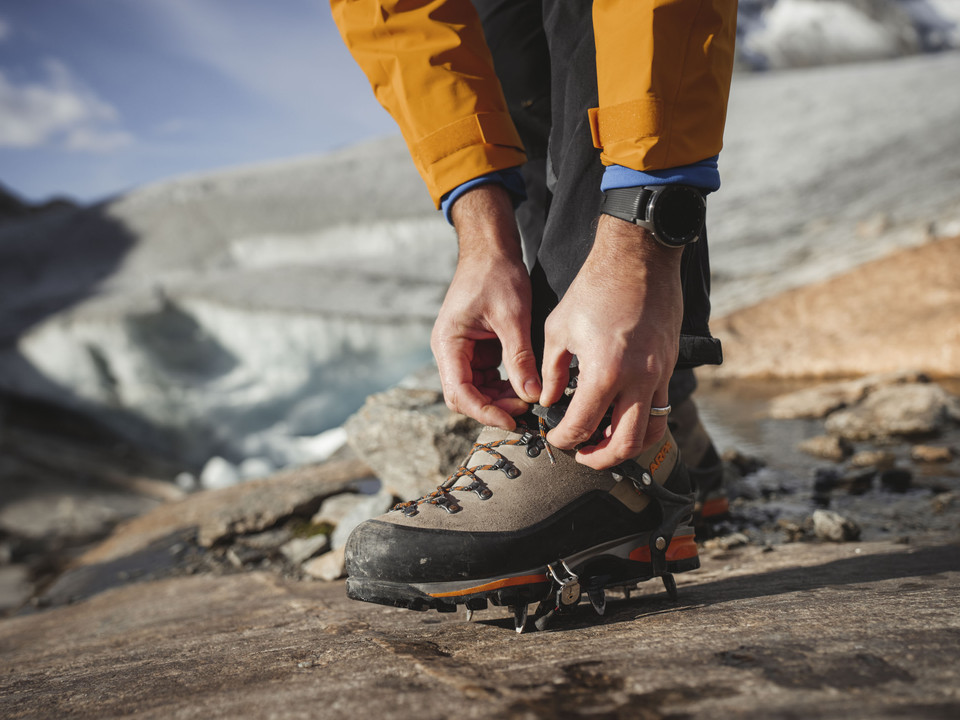 Putting on crampons before the glacier tour Teilnehmer der UNESCO Gletschertour Aletsch schnürt Bergschuhe mit Steigeisen am Rand des Aletschgletschers im WallisParticipants of the UNESCO Aletsch Glacier Tour lace up mountain boots with crampons on the edge of the Aletsch Glacier in ValaisUn participant au Tour du Glacier d'Aletsch de l'UNESCO chausse des chaussures de montagne avec des crampons au bord du glacier d'Aletsch en Valais