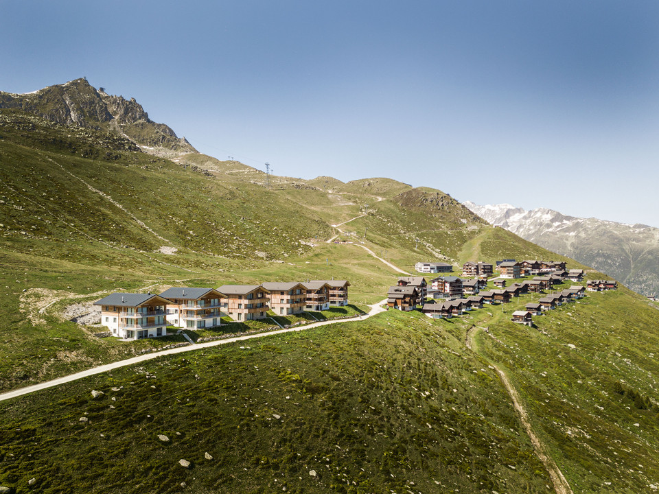 Summery view over Fiescheralp in Valais Fiescheralp im Sommer mit Chalets und Bergen, Ausgangspunkt für 2-Tage-Erlebnis Gletschertour AletschFiescheralp in summer with chalets and mountains, starting point for 2-day Aletsch glacier tour experienceFiescheralp en été avec chalets et montagnes, point de départ de l'expérience de 2 jours sur le glacier d'Aletsch