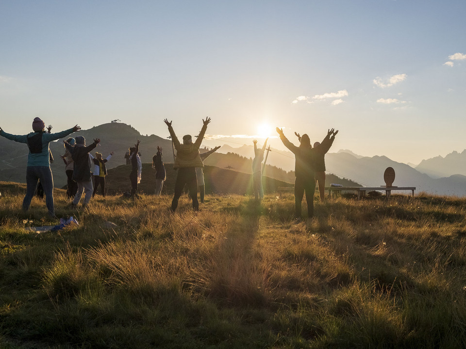 Yoga group at sunset on the Bettmeralp Gruppe von Menschen hebt die Arme im goldenen Licht beim Sonnenuntergang Yoga Aletsch Arena auf der BettmeralpGroup of people raising their arms in the golden light at sunset Yoga Aletsch Arena on BettmeralpGroupe de personnes levant les bras dans la lumière dorée au coucher du soleil Yoga Aletsch Arena sur la Bettmeralp