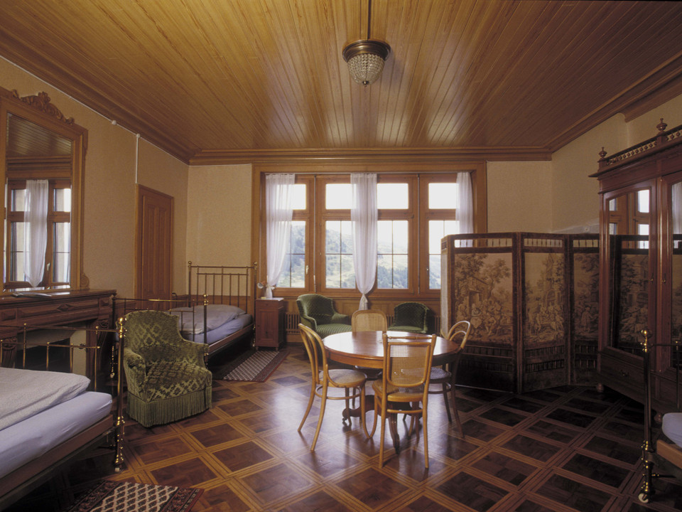 Gästezimmer der Villa Cassel im historischen Stil Historisch eingerichtetes Gästezimmer mit antiken Möbeln in der Villa Cassel während der Villa Cassel Aletschwald GeschichteHistorically furnished guest room with antique furniture in the Villa Cassel during the Villa Cassel Aletschwald HistoryChambre d'hôtes aménagée de manière historique avec des meubles anciens dans la Villa Cassel pendant l'histoire de la Villa Cassel Aletschwald