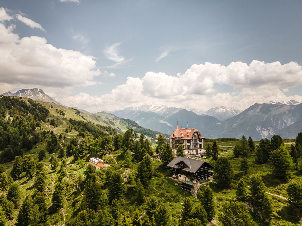 Vue aérienne de la Villa Cassel au milieu des montagnes Kräuterwanderung Aletsch Arena mit Panorama auf die Villa Cassel, eingebettet in die Bergwelt und den AletschwaldAletsch Arena herb hike with panoramic views of Villa Cassel, nestled in the mountains and the Aletsch ForestRandonnée sur le thème des herbes aromatiques dans l'Aletsch Arena avec panorama sur la Villa Cassel, nichée dans le paysage montagneux et la forêt d'Aletsch