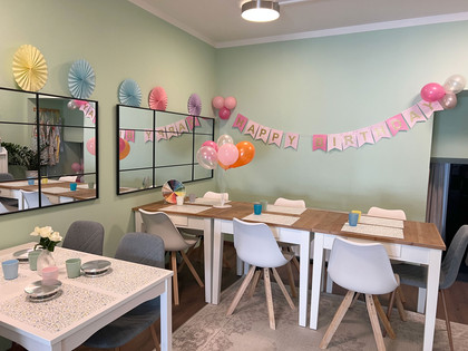 Lieblingstasse-innen.jpg Liebevoll dekorierter Raum mit Maltischen und Geburtstagsgirlande an der Wand