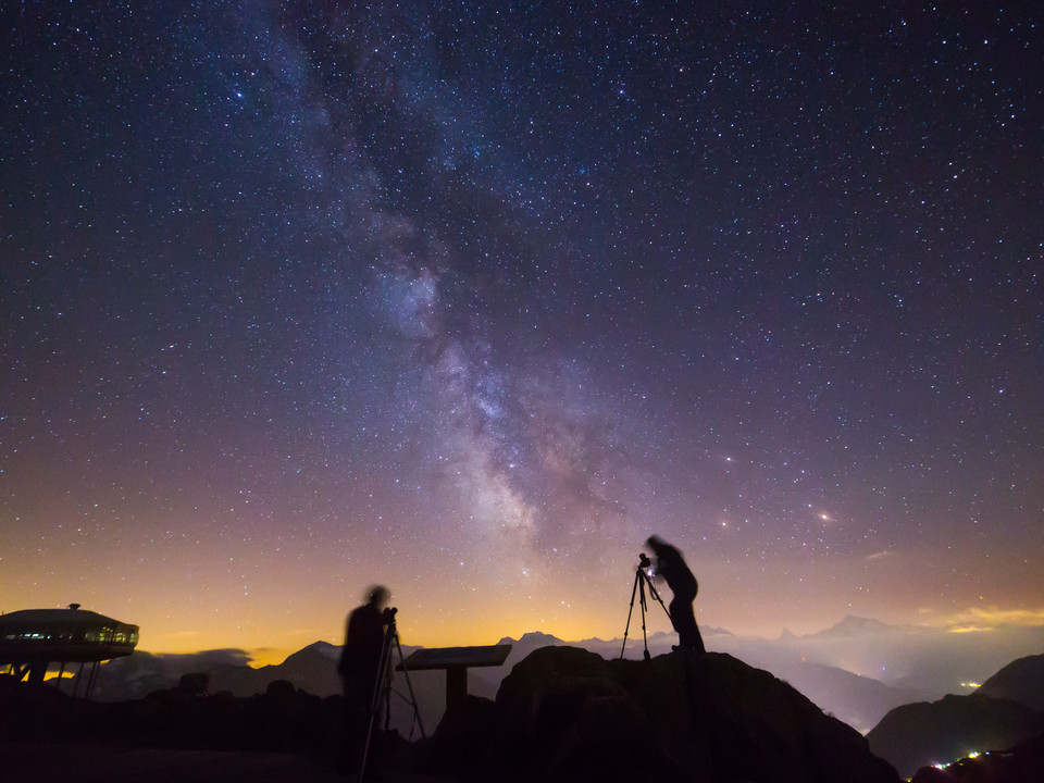 Astrophotographers under the Milky Way Sternenfotografie Bettmerhorn zeigt zwei Fotografen mit Stativen unter der leuchtenden Milchstrasse hoch über der Aletsch ArenaStar photography Bettmerhorn shows two photographers with tripods under the glowing Milky Way high above the Aletsch ArenaLa photographie d'étoiles du Bettmerhorn montre deux photographes avec des trépieds sous la voie lactée lumineuse au-dessus de l'Aletsch Arena.
