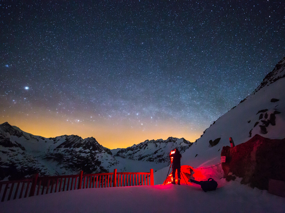 Fotograf bei Sternenfotografie am Bettmerhorn Sternenfotografie Bettmerhorn mit Fotograf und Stativ vor leuchtendem Nachthimmel über dem AletschgletscherStar photography Bettmerhorn with photographer and tripod in front of a glowing night sky over the Aletsch GlacierPhotographie d'étoiles au Bettmerhorn avec photographe et trépied devant un ciel nocturne lumineux au-dessus du glacier d'Aletsch