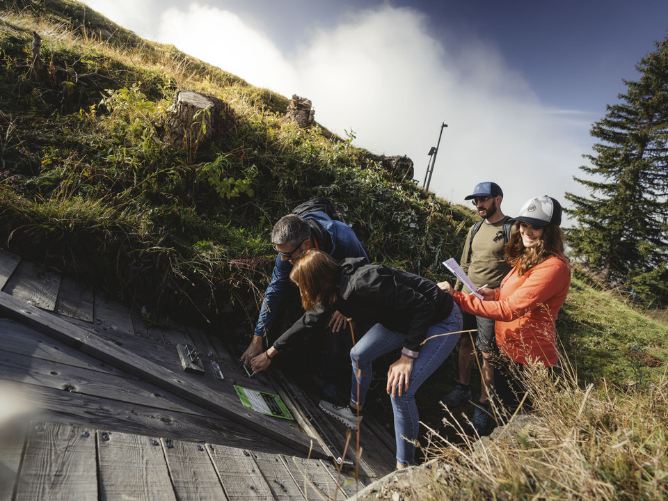 Solution de l'énigme du Foxtrail Foxtrail Desoria Aletsch Arena mit Teilnehmern, die an einer verborgenen Station ein Rätsel öffnen und Hinweise entschlüsselnFoxtrail Desoria Aletsch Arena with participants who open a puzzle and decipher clues at a hidden stationFoxtrail Desoria Aletsch Arena avec des participants qui ouvrent une énigme à une station cachée et déchiffrent des indices.