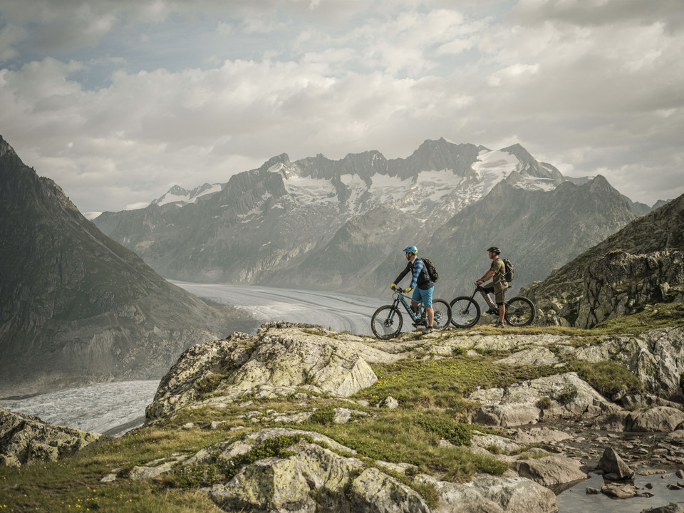 Biking with a view of the Aletsch Glacier Bike Genuss Tour Aletsch Arena mit Bikern oberhalb des Grossen Aletschgletschers auf einer genussvollen Panoramastrecke im WallisBike pleasure tour Aletsch Arena with bikers above the Great Aletsch Glacier on an enjoyable panoramic route in ValaisBike Genuss Tour Aletsch Arena avec des vététistes au-dessus du grand glacier d'Aletsch sur un parcours panoramique savoureux en Valais
