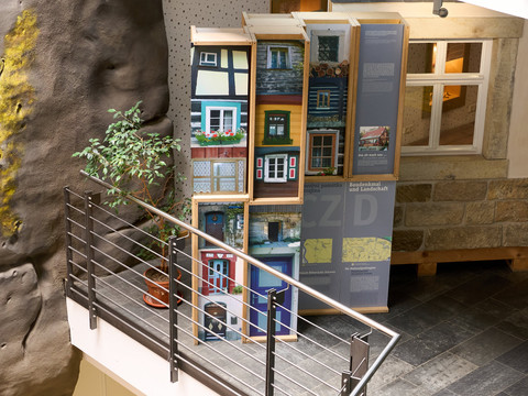 Nationalparkzentrum  Modell eines mehrstöckigen Gebäudes mit detaillierten Fenstern und Balkonen, ausgestellt auf einer Galerie.