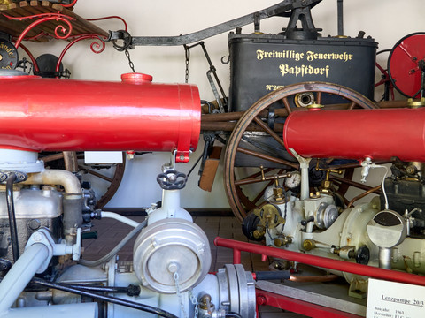 Feuerwehrmuseum Papstdorf Rote historische Feuerwehrspritze neben anderen alten Maschinen und Geräten.